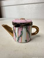 Side view showing full teapot shape, pink and white striped body, gold spout and handle