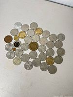 Spread of approximately 40 assorted casino tokens showing variety of finishes and sizes