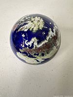 Overall view of cobalt blue Lundberg Studios paperweight showing globe motif