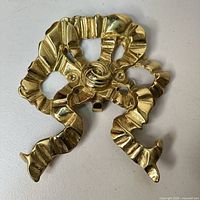 Front view of ornate polished brass ribbon-form applique