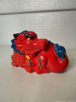 Front-side view of red ceramic dragon coin bank