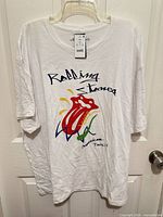 Front view of white Rolling Stones T-shirt on hanger showing full graphic and tag
