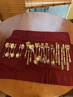 Full view of 25 assorted flatware pieces on burgundy roll case
