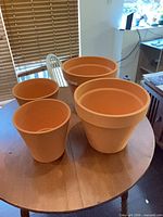 Four terracotta plant pots on table
