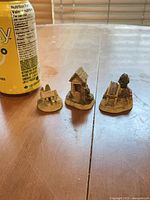 Three miniature cottages next to soda can for scale