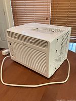 Front and left side view of Midea window A/C showing grille, housing, and power cord