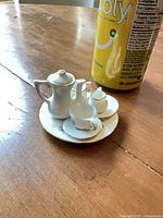 Full tea set on a plate beside a soda can for scale