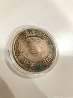 Obverse view of coin in capsule showing bust and Chinese characters