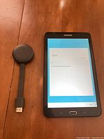 Tablet powered on at Wi-Fi setup screen beside Chromecast dongle