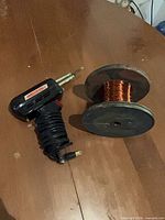 Soldering gun and copper wire spool on table