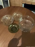 Four bowls grouped on table: large etched bowl, two clear pressed bowls, one green bowl
