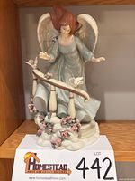 Front view of porcelain angel figurine showing full design, doves, roses and railing