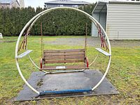 Full view of circular metal frame garden swing on pad