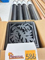 Box containing stacked oak-leaf medallions and four black lantern fixtures