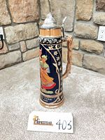 Front view of tall German beer stein showing design and lid