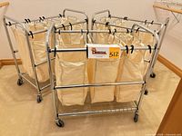 Group of three stainless rolling laundry carts with canvas bags