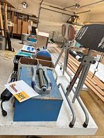 Overall view of table showing Ridgid stands, Curtis drawer box, grey manual tool, hardware boxes, tray of sockets