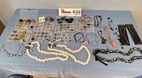 Overview of lot with necklaces, bracelets, earring organizers and packaged pieces on table