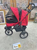 Side profile of red Pet Gear three-wheel stroller, canopy closed
