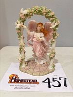 Front view of Cassandra figurine under floral arch showing overall design and signed base