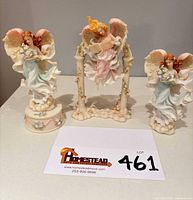 Front view of three angel figurines and display base