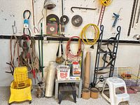 Overall view of dolly, mop bucket, cords, bench, tubes, step stool, lamp, chain hoist on wall