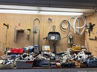 Wide shot of pegboard with hanging tools and bench covered in hardware