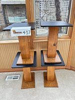 Front view of four wood pedestal side tables stacked to show design and finish