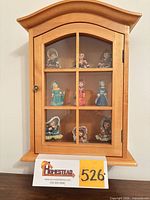 Front view of cabinet with glass door closed showing figurines on three levels