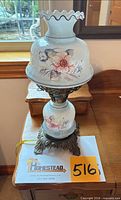 Front view of lamp showing painted floral glass shade and metal base
