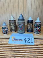 Front view of all five steins showing designs and size variation