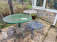 Overall view of three metal tables and wire plant stand on patio