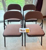 Front view of four matching upholstered metal folding chairs