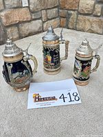 Front view of all three ceramic beer steins with lot tag