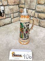Front view of ceramic beer stein showing relief lovers scene and pewter lid