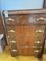 Full front view of 4-drawer dresser showing wood veneer and brass cup pulls
