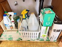 Overall view of trays containing cleaning bottles, spray bottles, vinegar jug and boxed bags