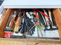 Drawer view showing majority of knives, honing rod, portioner box, injector, measuring spoons and shears
