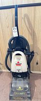 Front view showing Bissell PowerSteamer DirtLifter upright carpet cleaner, clear tank and nozzle