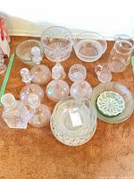 Overall lot showing variety of clear and green glass items including decanters, bowls, pitcher, compote