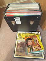 Black record case filled with vinyl LPs, additional records and sleeves beside it