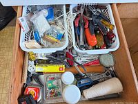 Drawer with two baskets of hand tools and hardware visible
