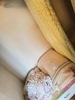 Stack of blankets showing yellow quilted bedspread upright and others folded