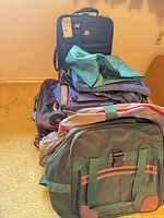 Stacked assortment of rolling suitcases, duffel/backpack and garment bag