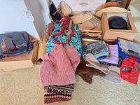 overview of pile showing hats, scarves, sweater, gloves, belt, boxes