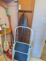 Step stool, ironing board, bin, and partial floor polisher in storage area