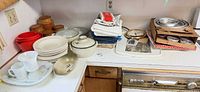 Overview of lot on countertop showing plates, bowls, casserole, platter, cups, linens, wooden canisters, mixing bowls, scale, tart pans