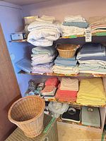 Shelves with folded linens, towels, wicker baskets and two analog scales