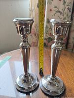 Both candlesticks standing beside tape measure showing height