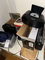 Tabletop with Sony boombox, silver boombox, cassette deck, storage case and records